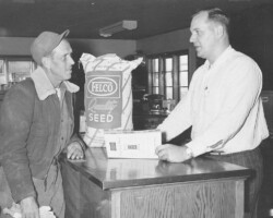 Farmer's Coop Exchange Pella employee selling feed to a customer; 1968